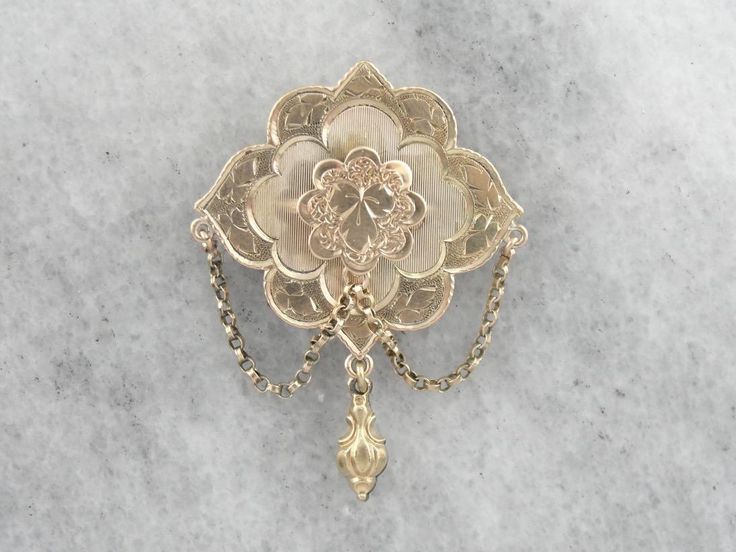 Dating to the height of the Victorian Era, this vintage brooch features all the small details that the era is known for. Delicate engraving over warm yellow gold crowns the top, giving the traditional gold a soft texture. Particularly nice is the echo of the ivy motif on the scalloped frame. Love this piece but want to make it more versatile, we here at Market Square Jewelers along with our master metalsmiths can convert this fantastic brooch into a necklace or pendant for an additional fee, ple Antique Brooch With Intricate Pendant Design, Antique Pendant Brooch With Intricate Design, Antique Yellow Gold Brooches With Intricate Design, Ornate Engraved Brooch, Traditional Yellow Gold Collectible Brooch, Ceremonial Gold Brooches With 17 Jewels, Traditional Yellow Gold Pendant Brooches, Traditional Yellow Gold Brooches For Formal Occasions, Traditional Yellow Gold Formal Brooches