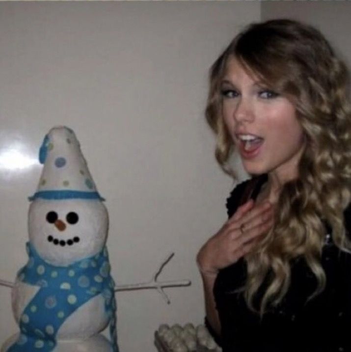 a woman standing next to a snowman with her hands on her chest and mouth open