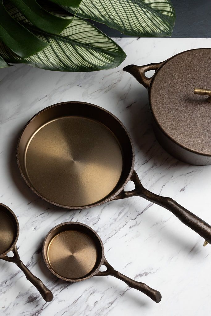 three pots and two pans on a marble table