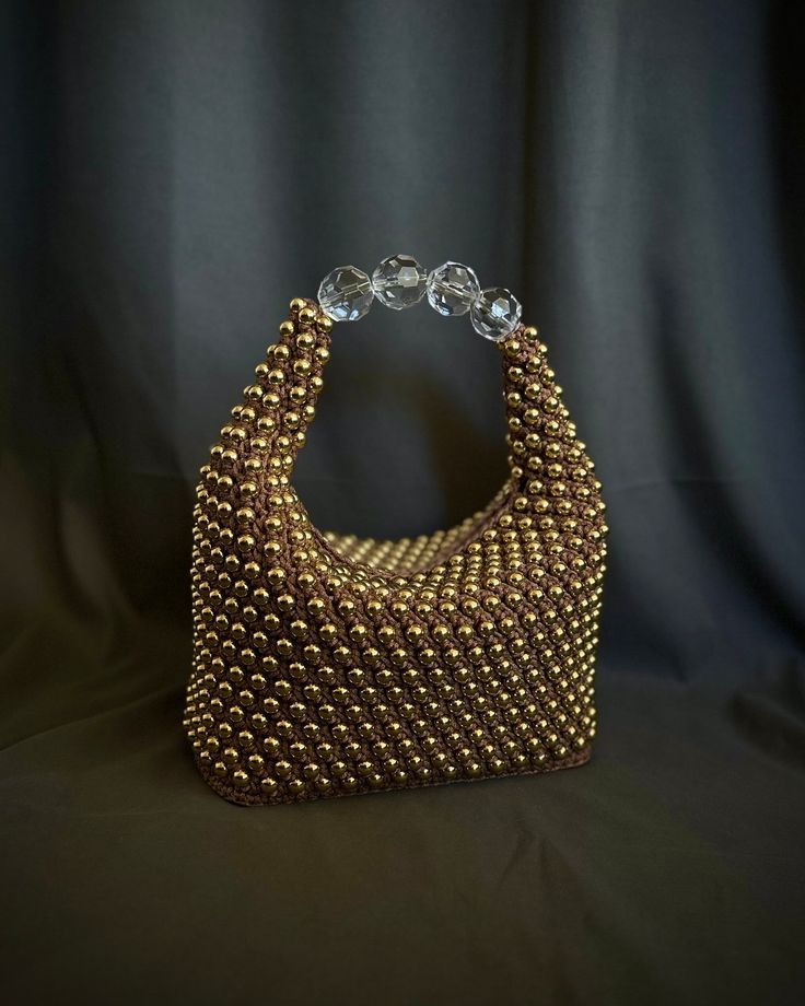 a gold beaded purse sitting on top of a black cloth