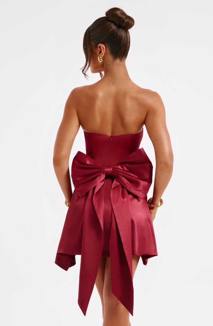 The Freja mini dress is party perfection. Crafted in luxurious stretch satin, this beautiful design is strapless with a corseted bodice and flirty, flouncy skirt. A dramatic bow to the back finishes the look.   Colour: Burgundy. Luxury stretch satin. Oversized bow to back. *Detachable.  Strapless. Corset body. Zip fastening to reverse. Mini length. Model is an XS and is wearing an XS. Homecoming Dresses Corset, Midi Dress Wedding Guest, Burgundy Mini Dress, Maxi Dress Sale, Strapless Corset, Sparkle Dress, Dresses By Length, Stretch Satin, Formal Dresses Prom