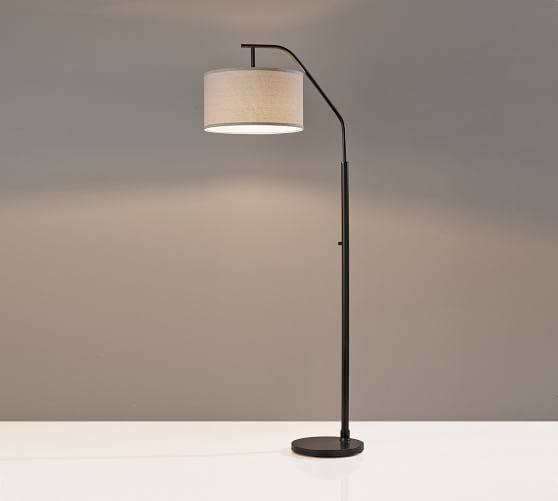 a floor lamp with a white shade on it's side and a gray wall in the background