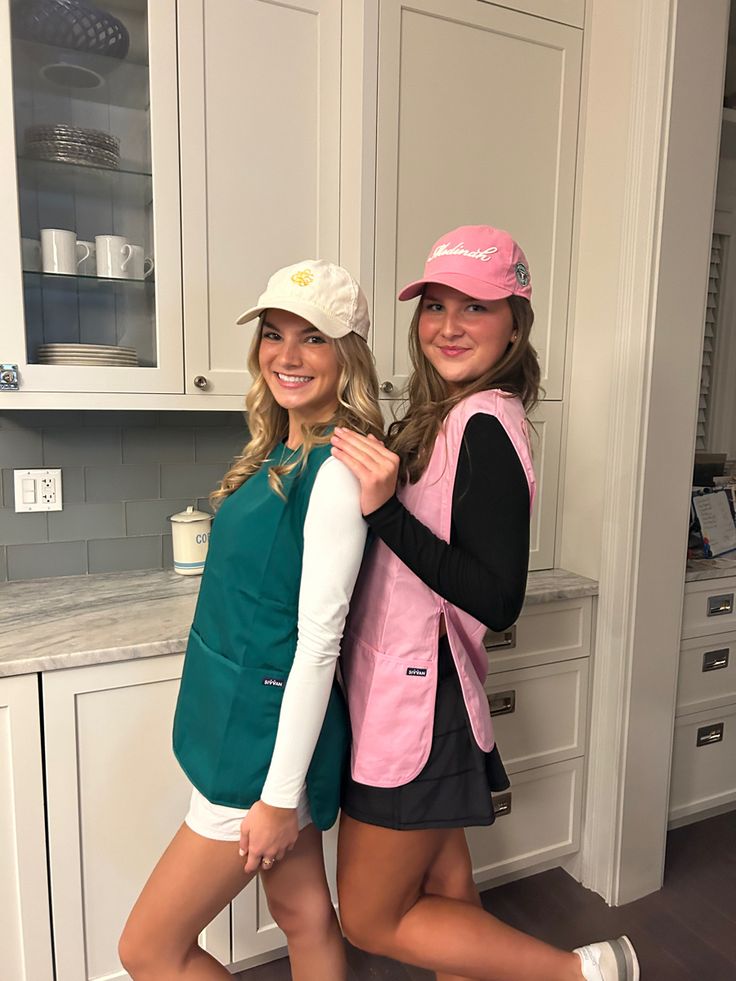 two young women standing next to each other in a kitchen with white cabinets and counter tops