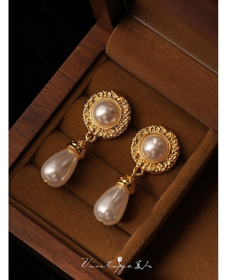 a pair of gold and pearl earrings in a box