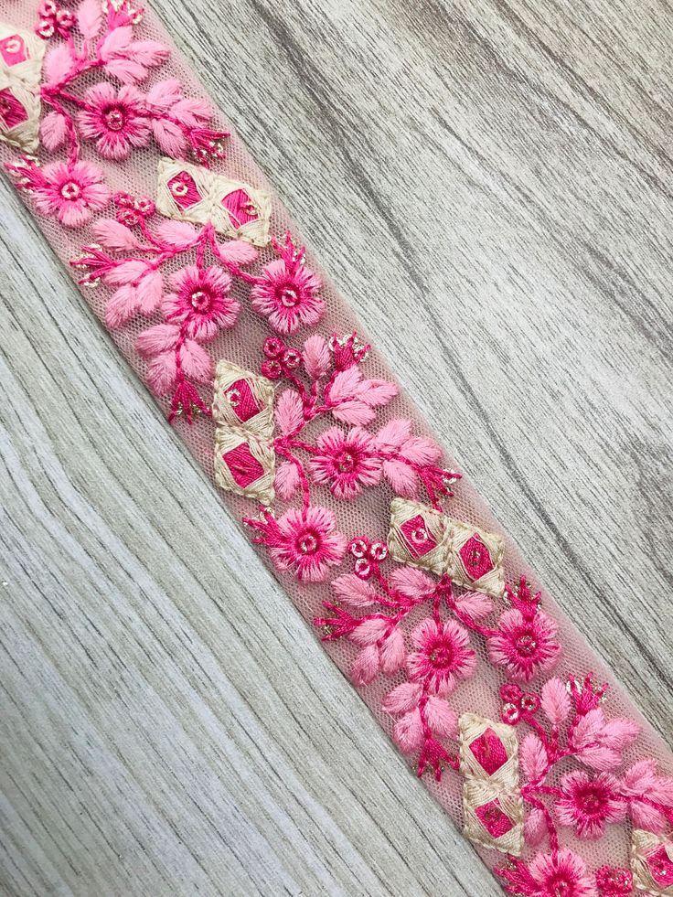 pink and white flowers are on a sheer ribbon with gold trimming around the edge