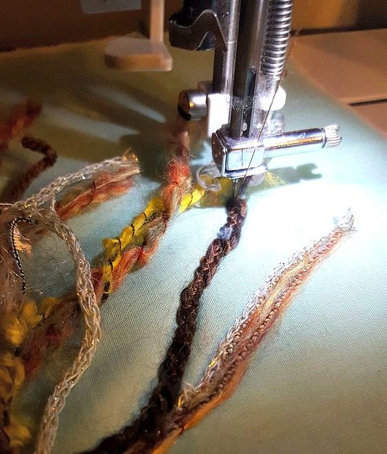 the sewing machine is working on many different colored thread and bead pieces that are being sewn together