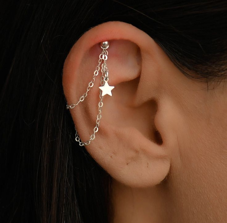 a woman's ear with a chain attached to it and a star on the side