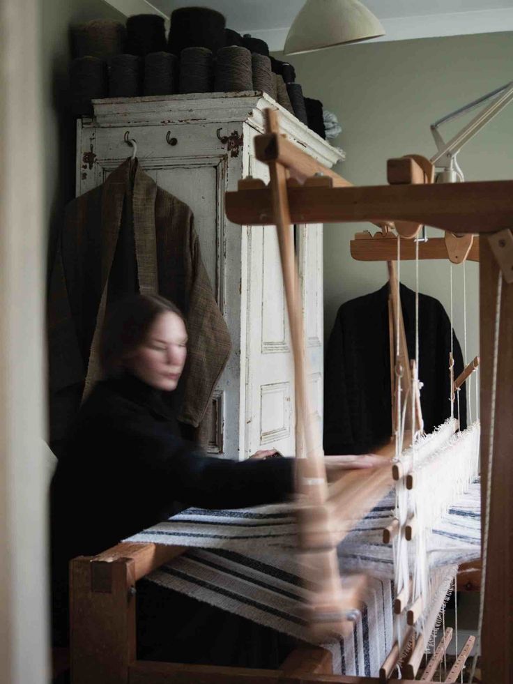 a woman is weaving fabric on an old loom