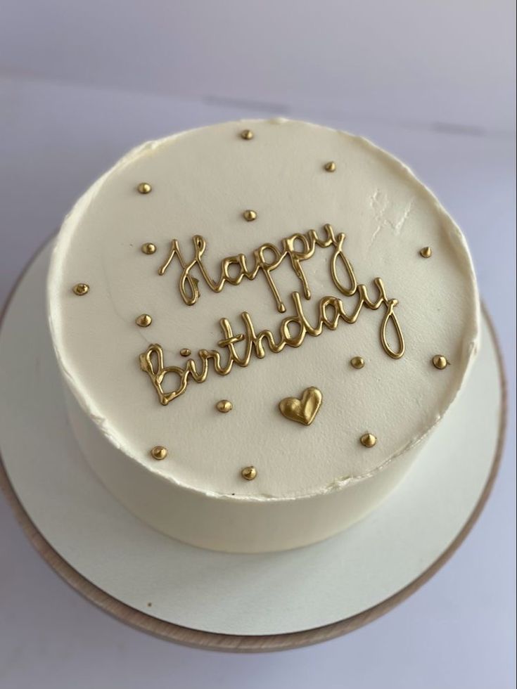 a white birthday cake with gold confetti and happy birthday written on the top