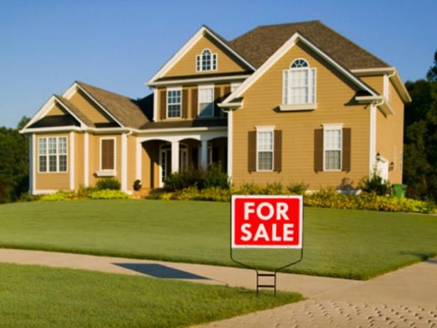 a for sale sign in front of a large house with lots of grass and bushes