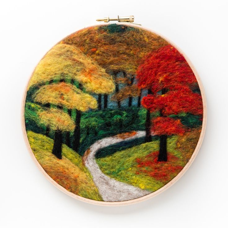 an embroidery project with trees and a road in the middle, on a white surface