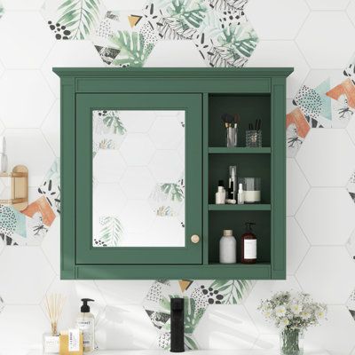 a bathroom vanity with green cabinet and mirror next to wallpapered walls in the background