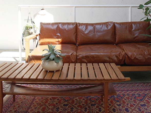 a brown leather couch sitting next to a wooden coffee table on top of a rug