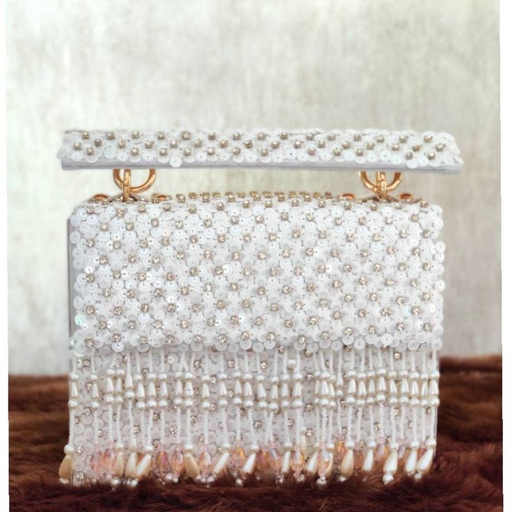 This stunning Party hand Bag is embellished with pearls and hanging on a white silk Base . This Minaudière Clutch is ideal for parties and weddings and any festive occasion. This Handmade Embroidered Embellished Sling Purse can be used with or without the metal sling that is included. Dazzle through the Day or Evening with this beautifully Handcrafted Wedding Bridal Clutch Bag. Perfect for a Bride, Bridal Gift, Bridal Clutch, Wedding Clutch, Mehndi, Nikaah, Shaadi, Sangeet, Indian and Pakistani White Evening Bag With Pearl Embroidery For Party, Pearl White Beaded Shoulder Bag For Party, Traditional Evening Shoulder Bag With Pearl Handle, Festive Pearl Embroidered Evening Bag For Party, Traditional Evening Clutch With Pearl Handle, Elegant Pearl Embroidered Shoulder Bag For Festive Occasions, Elegant Pearl Embroidery Shoulder Bag For Festive Occasions, Handmade White Clutch For Party, Traditional Party Evening Bag With Pearl Embroidery