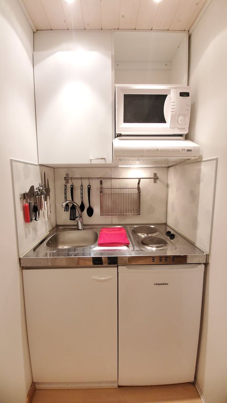 a small kitchen with white cabinets and stainless steel appliances on the counter top, along with utensils