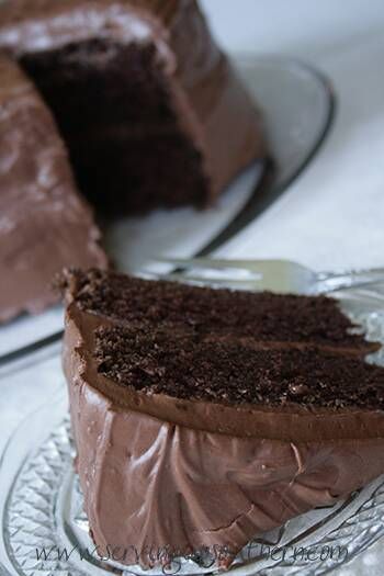 a chocolate cake on a glass plate with one slice cut out and the rest half eaten