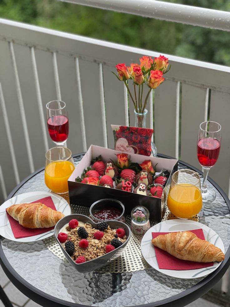 a table topped with plates of food and glasses of orange juice on top of a metal table