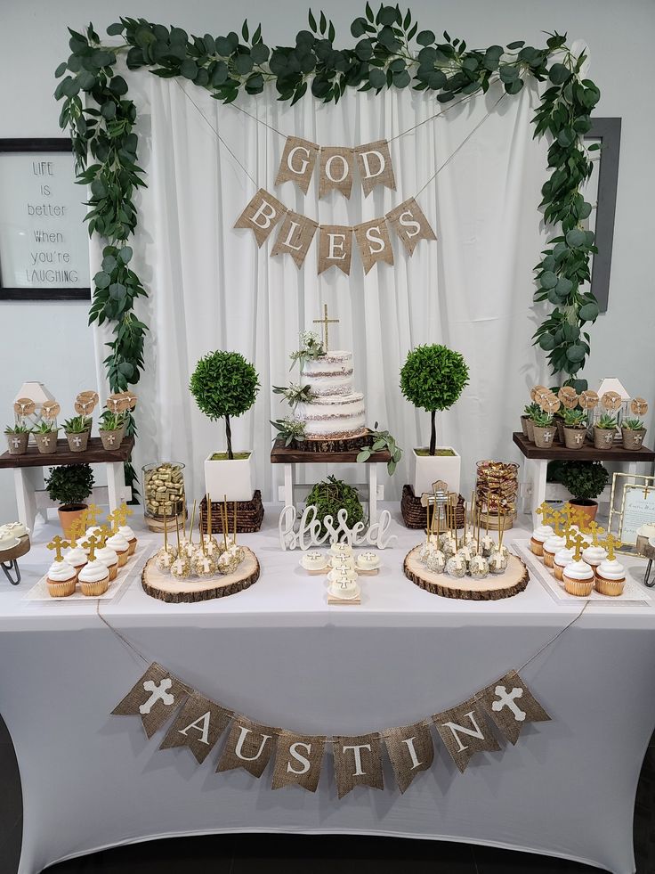 a table topped with cakes and cupcakes covered in greenery