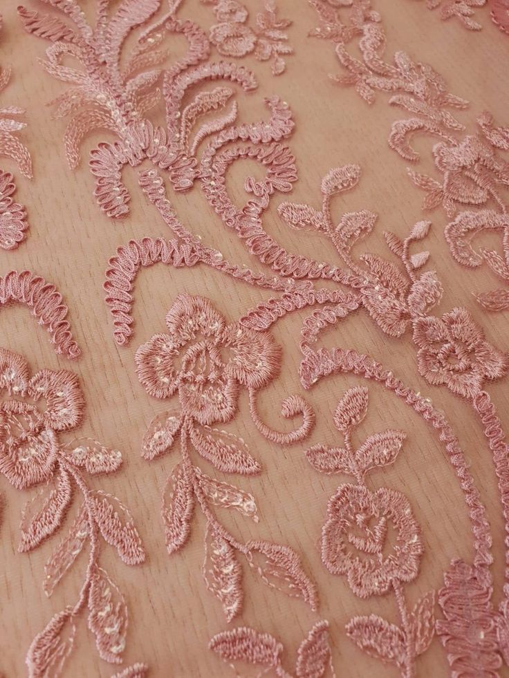 the back of a woman's dress with pink flowers and leaves embroidered on it