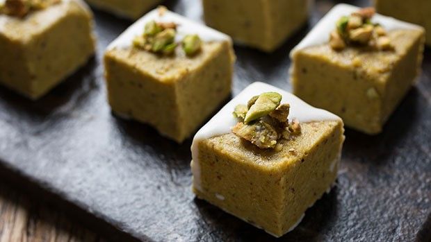 several square pieces of food with nuts on top sitting on a wooden tray, ready to be eaten