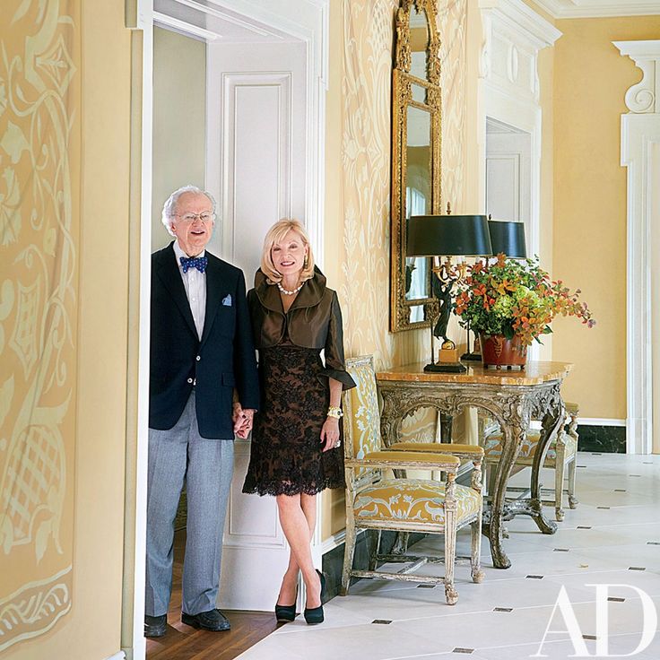 an older man and woman standing next to each other in front of a door way