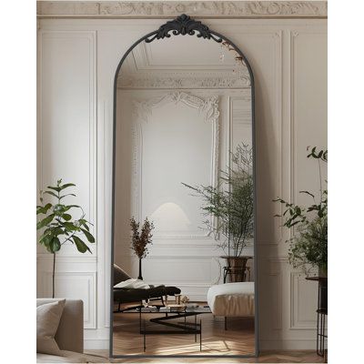 a large mirror in the middle of a living room with plants and couches around it