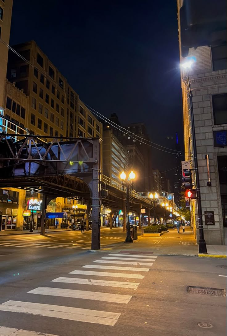 an empty city street at night with traffic lights and buildings in the background that are lit up