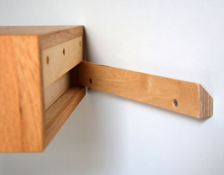 a close up of a wooden shelf on a white wall with holes in the wood