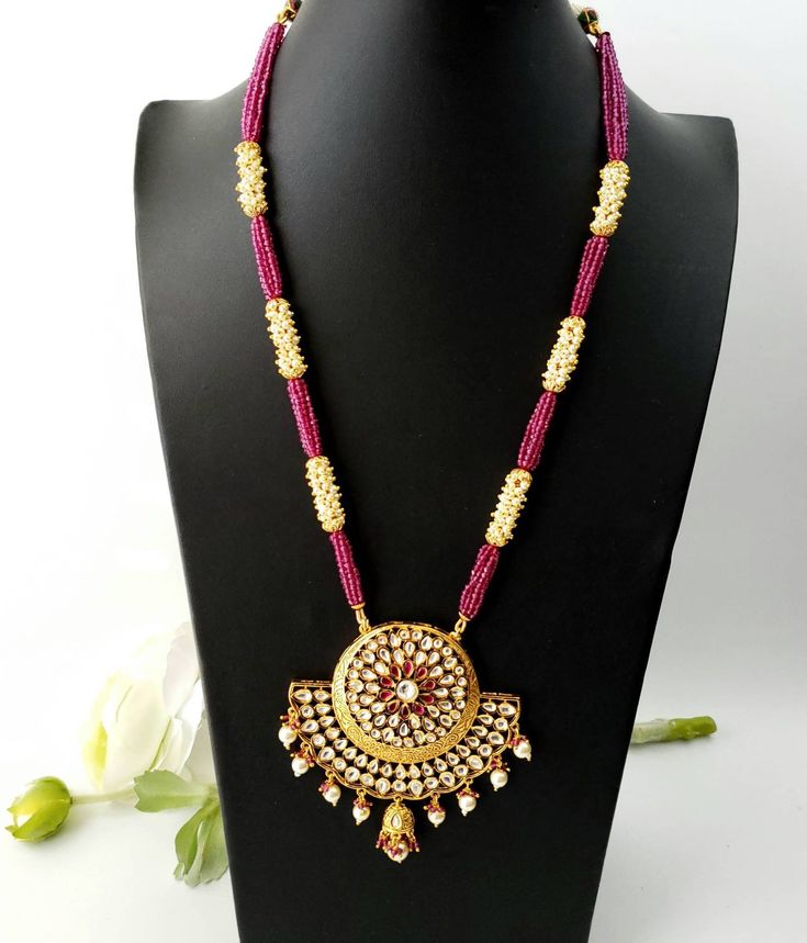 Look beautiful and feel beautiful wearing this gorgeous Indian kundan and pearl pendant necklace in chandbali design. Bright yellow gold colored crescent moon surrounds a stunning pattern of tear drop shaped kundan, which catches the light so nicely! The necklace is outstanding - lush and full multi strand necklace of sparkly faceted red crystals alternating with glowing, delicate tiny pearls. Matching jhumka earrings with pearls and red crystal accents, and clear and red stones. Effect is stunn