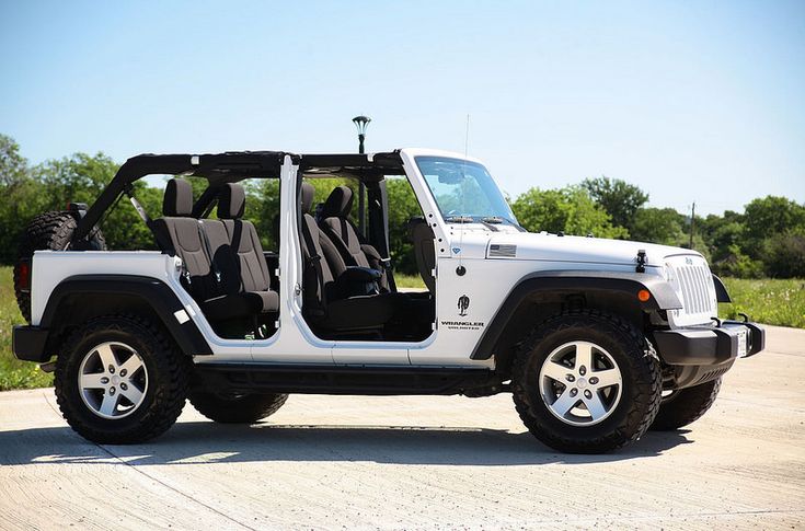 a white jeep is parked on the side of the road with its doors open and it's seat up