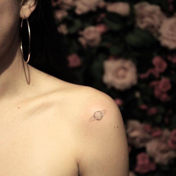 a woman with a small saturn tattoo on her chest