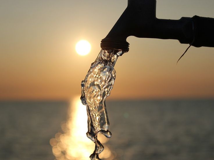 a water faucet with the sun setting in the background