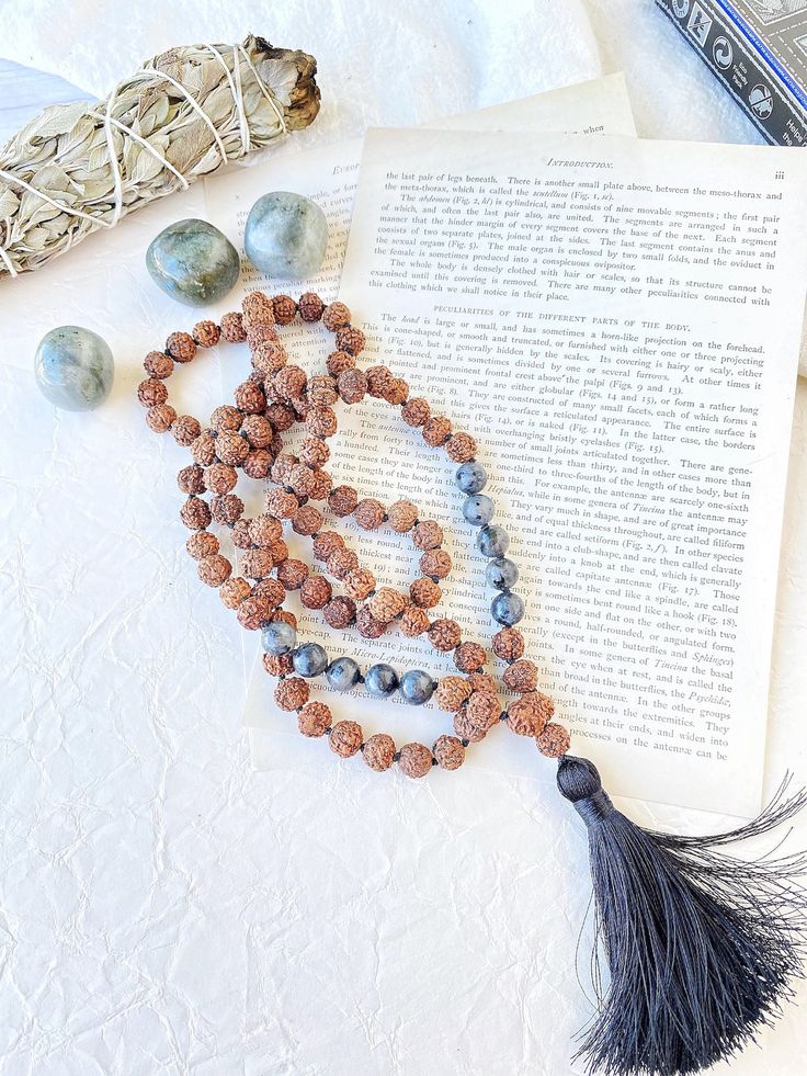 "Natural Rudraksha seeds and labradorite mala garland for meditation made by hand for me. 108 knotted bead garland for counting mantras.  With these seeds, traditionally used to pray in Hinduism and Buddhism, malas or Hindu rosary are made, which must have 108 beads (a \"magic\" number in Hinduism).  But they are also widely used in traditional Indian medicine for their supposed healing properties. In this mala we combine the mystique of rudraksha seeds with different stones that complement each other, resulting in very special jewels  I make each mala by hand, knotting each of the 108 beads with great care and I made every single silky and delicate tassel. I use a very resistant braided macrame rope, achieving a mala that lasts over time. This sacred mala necklace has 108 knotted beads of Spiritual 108 Beads Mala For Yoga, Spiritual Mala With 108 Beads For Festival, Holistic Mala With 8mm Beads For Festivals, Holistic Hand-strung Mala For Meditation, Spiritual Hand Knotted Beaded Necklaces For Festivals, Spiritual Hand Knotted Beaded Necklace For Festivals, Bohemian Mala With 108 Beads For Meditation, Spiritual 108 Beaded Jewelry For Yoga, Spiritual Yoga Mala With Round Beads