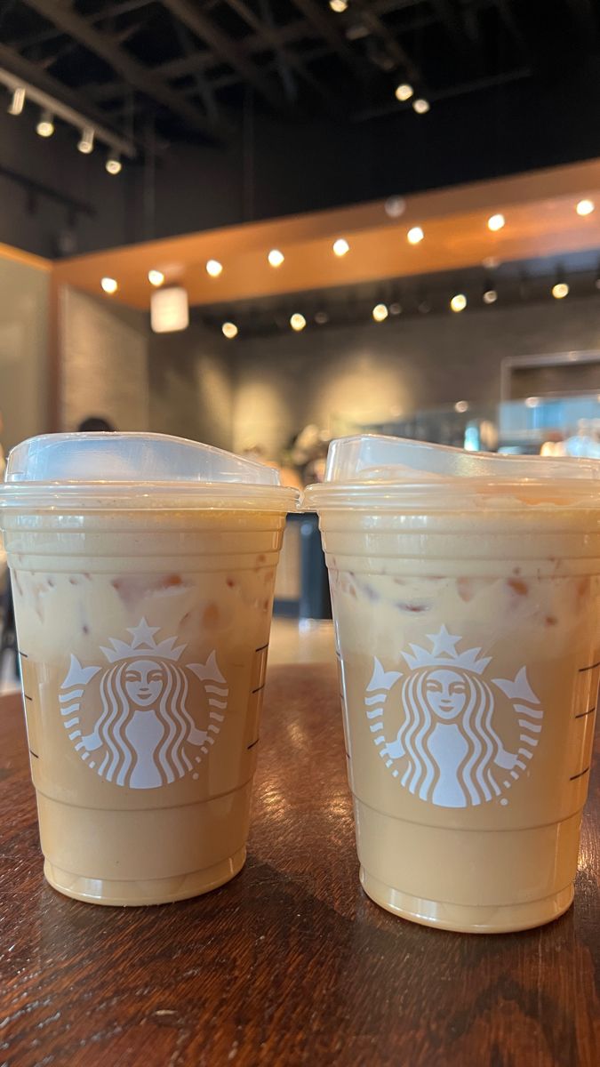 two starbucks drinks sitting on top of a wooden table