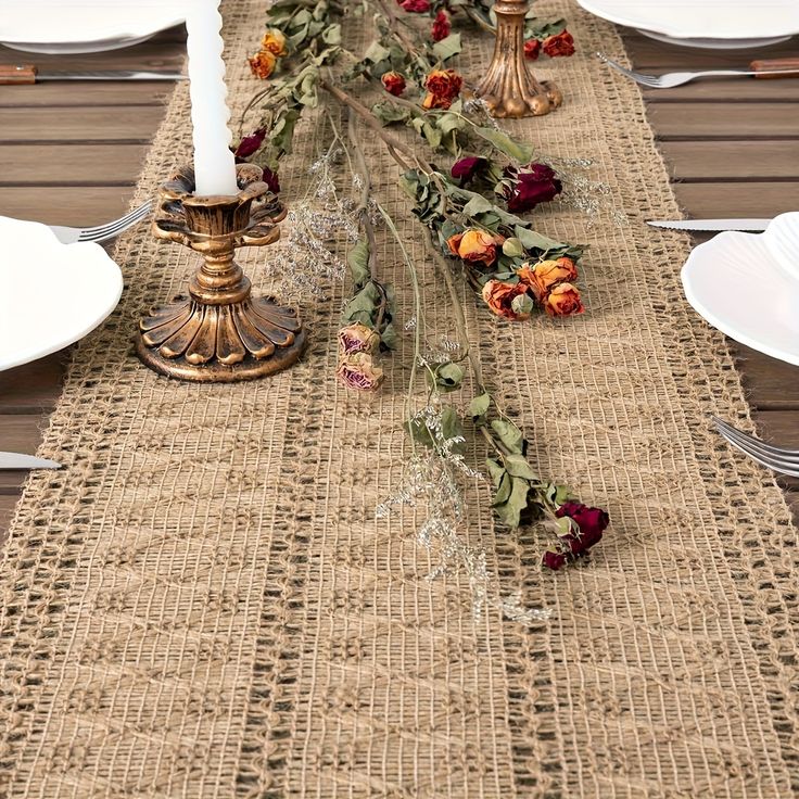 the table is set with white plates, silverware and candlesticks on it