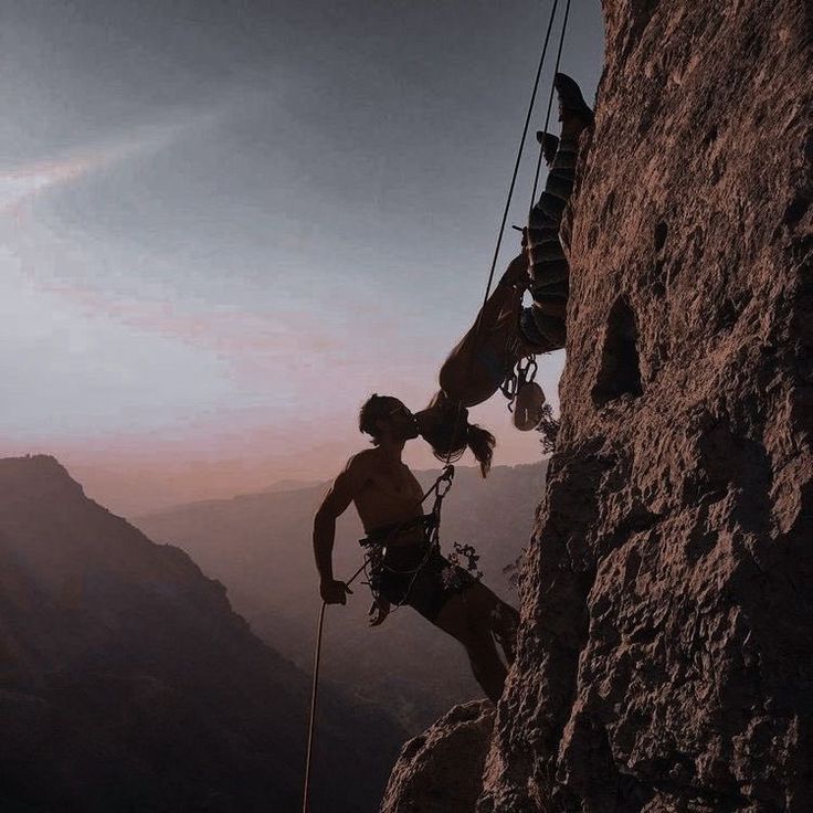 a man climbing up the side of a mountain while holding onto a rope with his hands