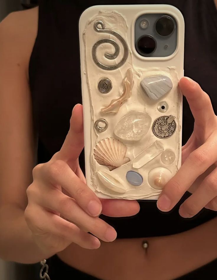 a woman holding a phone case with shells and seashells on it in her hands