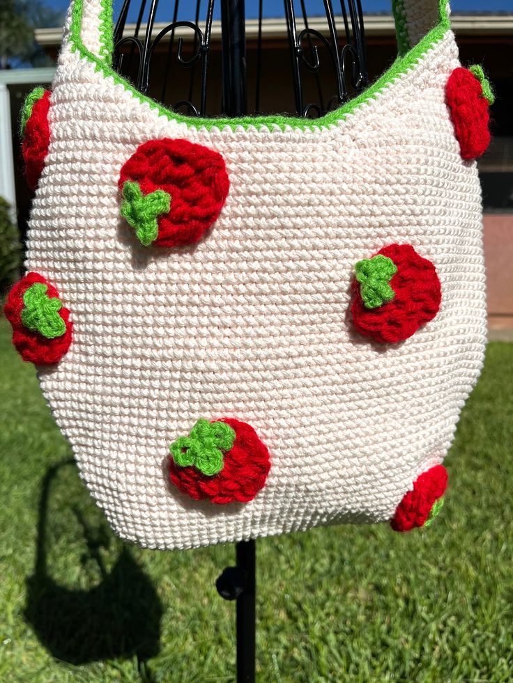 a crocheted purse with strawberries on it sitting on top of a stand