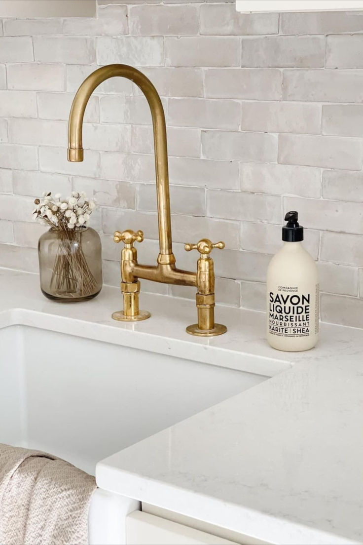 a white sink sitting under a faucet next to a bottle of lotion