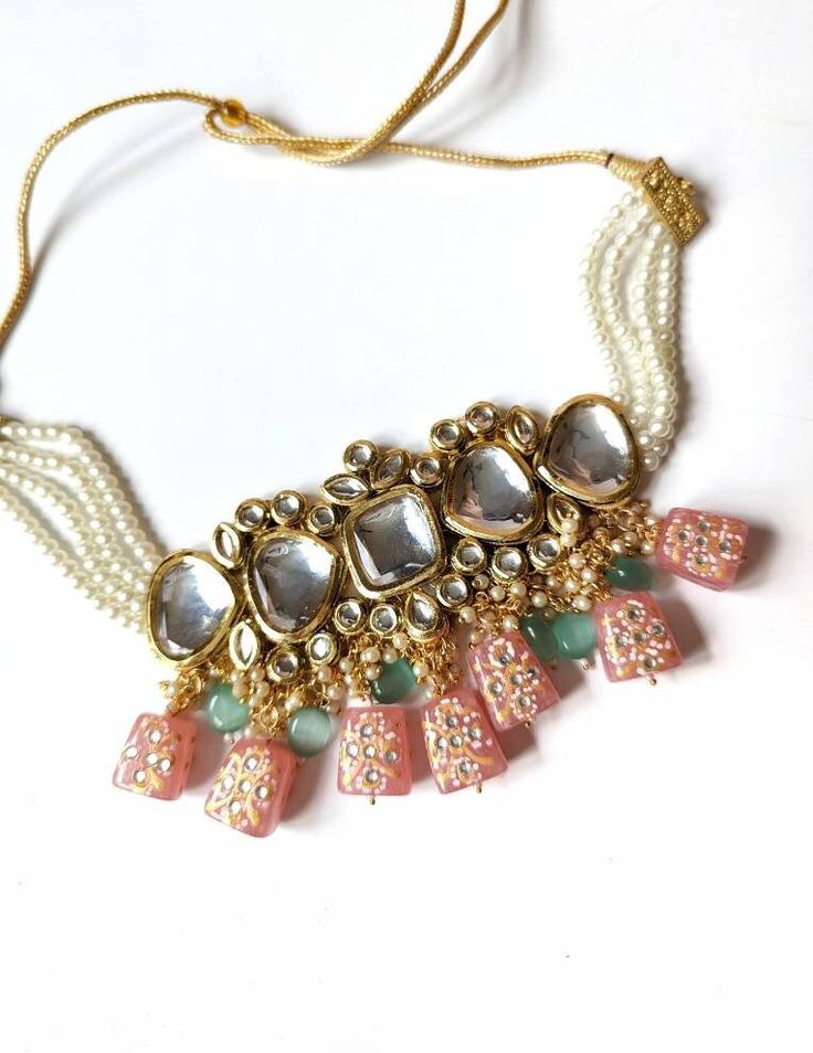 Studded with large sized kundan stones and handpainted glass danglers, this is a stunning choker. Comes with matching earrings. Color is peach. Dori/cord for adjustment! Choker width 2.63 inches Earrings length 2.90 inches Handmade Bollywood Kundan Jewelry Sets, Handmade Chandbali Kundan Bridal Necklace, Handmade White Kundan Beaded Necklaces, Bohemian Kundan Necklace With Stone Work, Handmade White Kundan Beaded Necklace, Festive Handmade Kundan Bridal Necklace, Handmade Kundan Bridal Necklace For Diwali, Temple Style Kundan Beaded Necklace, Kundan Necklaces With Dangling Beads For Gift