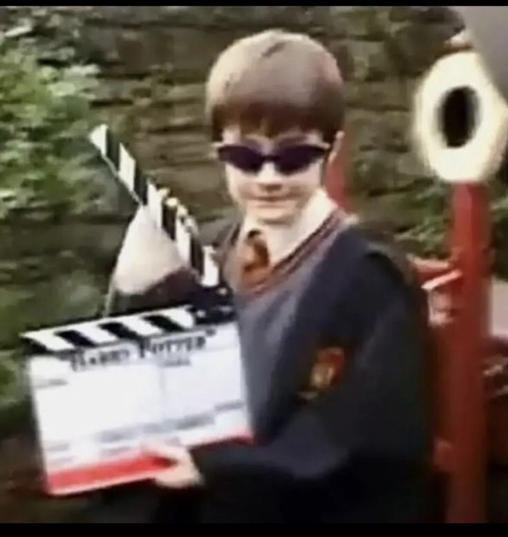 a young boy holding a movie clapper in front of him