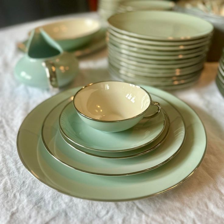 a table topped with plates and bowls on top of a white cloth covered tablecloth