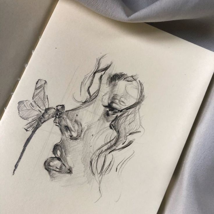 a pencil drawing of a woman's face with a flower in her hair, on top of a sheet of paper