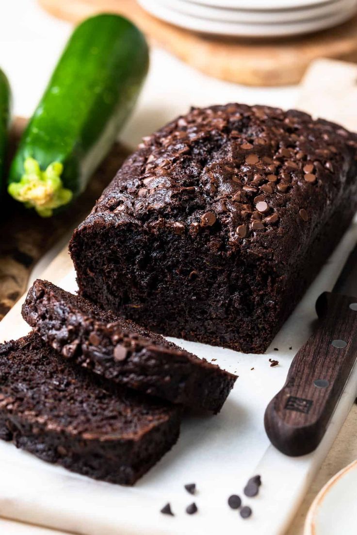 a loaf of chocolate zucchini bread sitting on top of a white cutting board