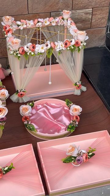 a table with pink and white flowers on it next to two boxes filled with cake