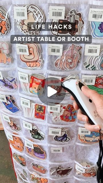 a person holding a computer mouse in front of a wall full of stickers with words life hacks artist table or both