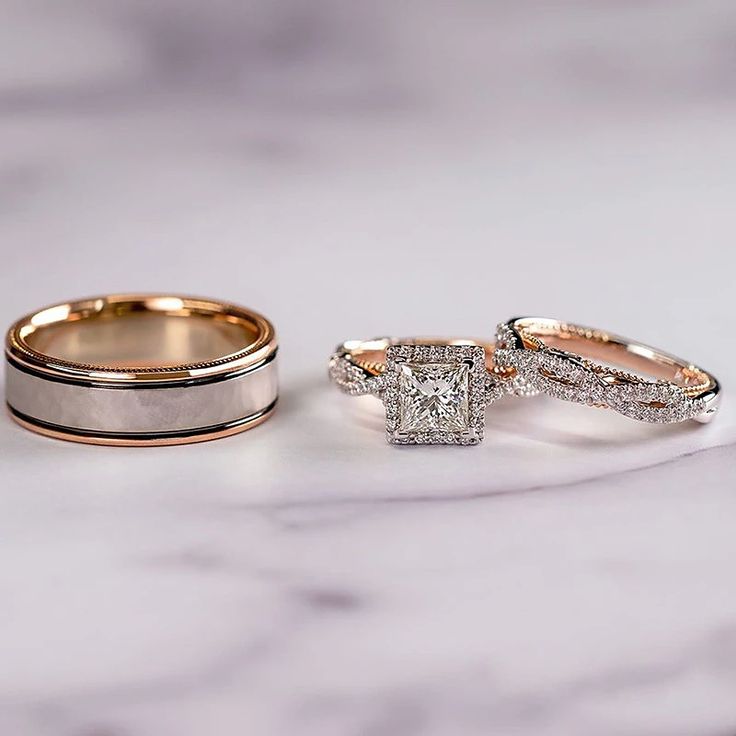 two wedding rings with one diamond on top and the other in gold, sitting on a marble surface