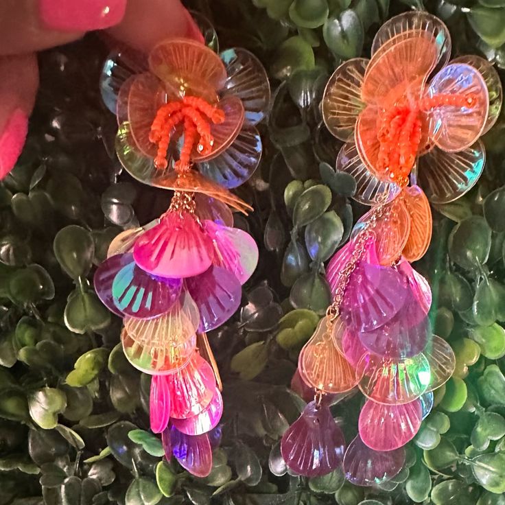 the earrings have been made from glass and are hanging on green plants with pink flowers