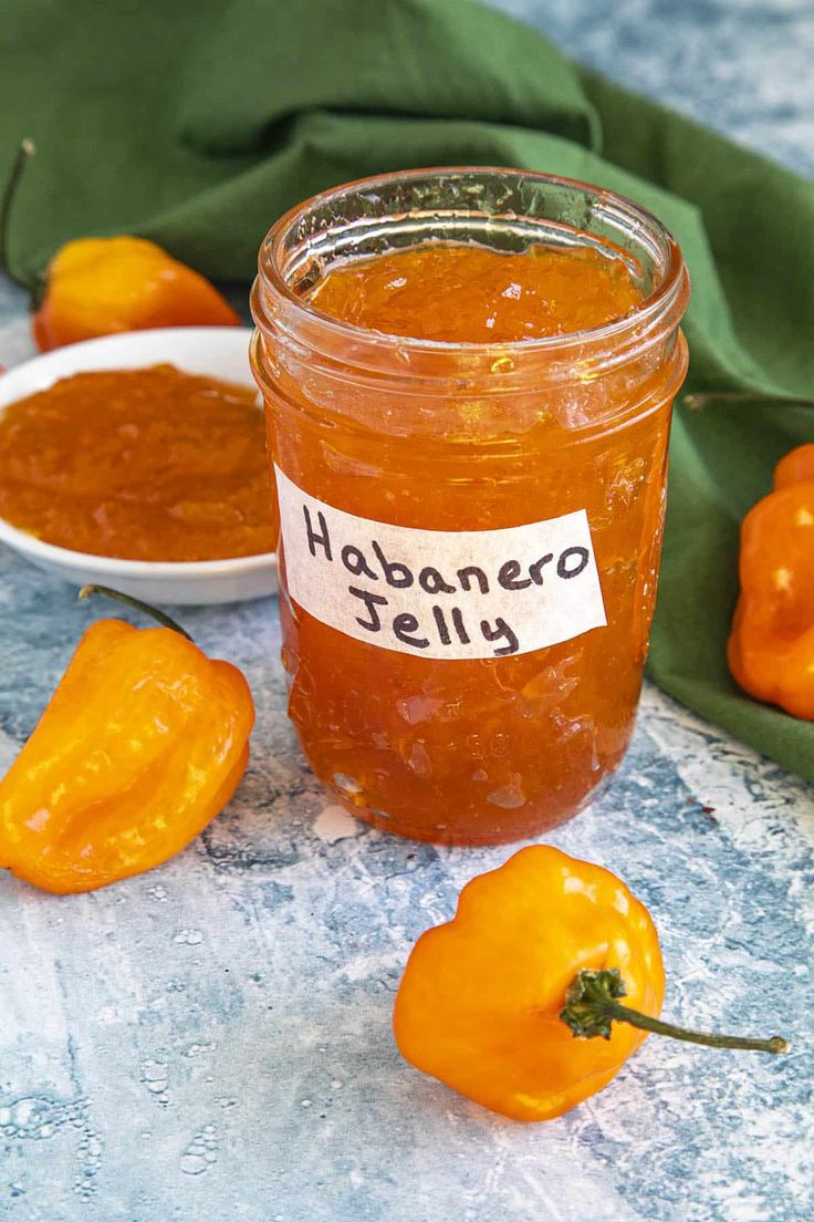 an open jar of jalapeno jelly next to some peppers on a table