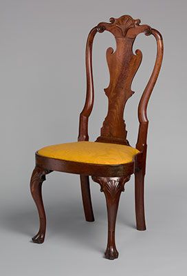 an antique chair with yellow upholstered seat and wooden frame, on grey background